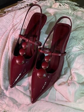 Pointed Burgundy Patent Slingback Kitten Heels with Decorative Button Accents.